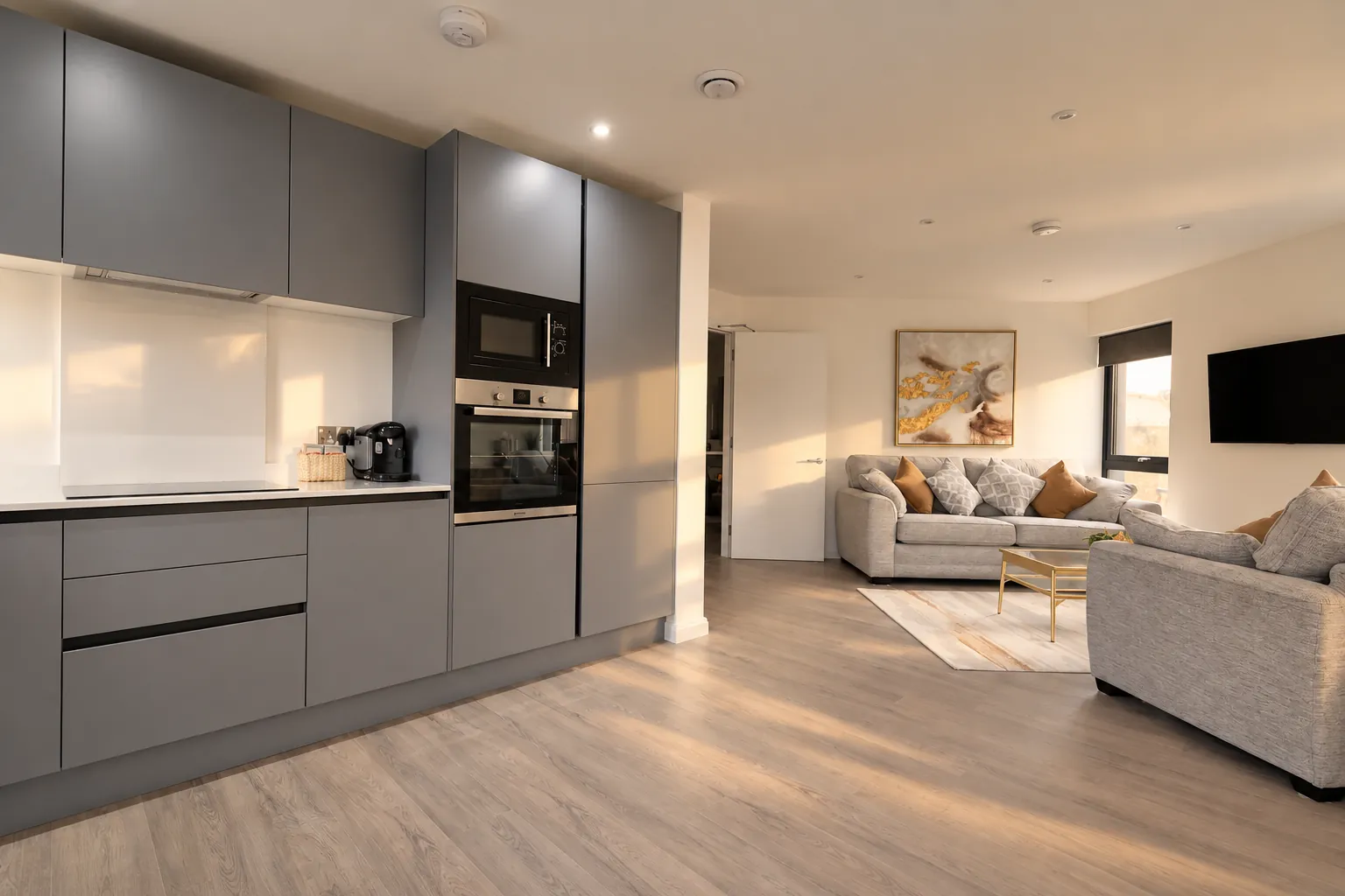 Grey handleless kitchen opening onto the living space in a Belfast apartment