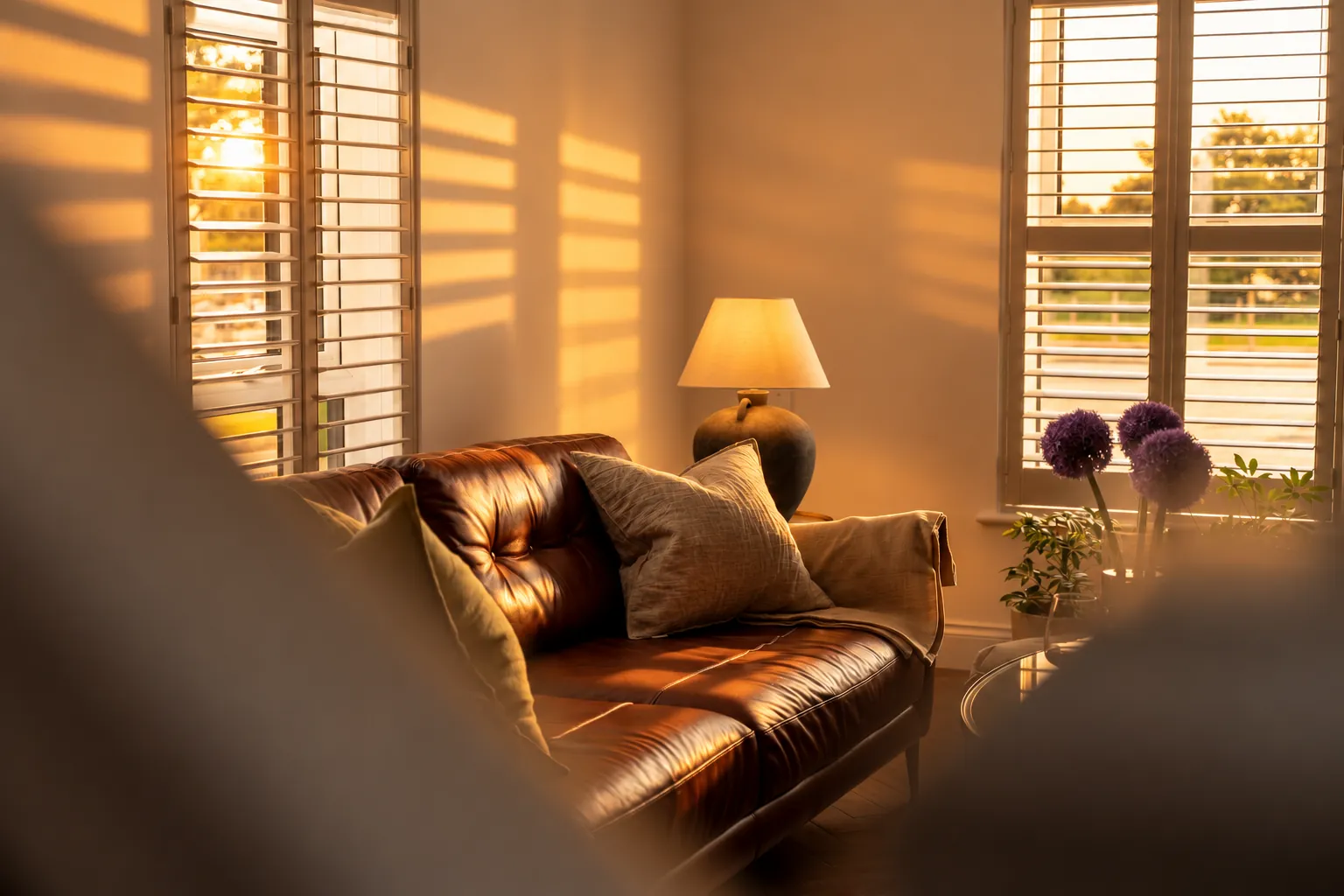 Leather sofa and stone lamp between shuttered windows as the sun sets, Bushmills
