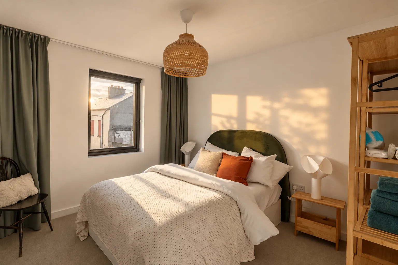 Townhouse bedroom with green velvet headboard and rattan pendant, sun on the wall