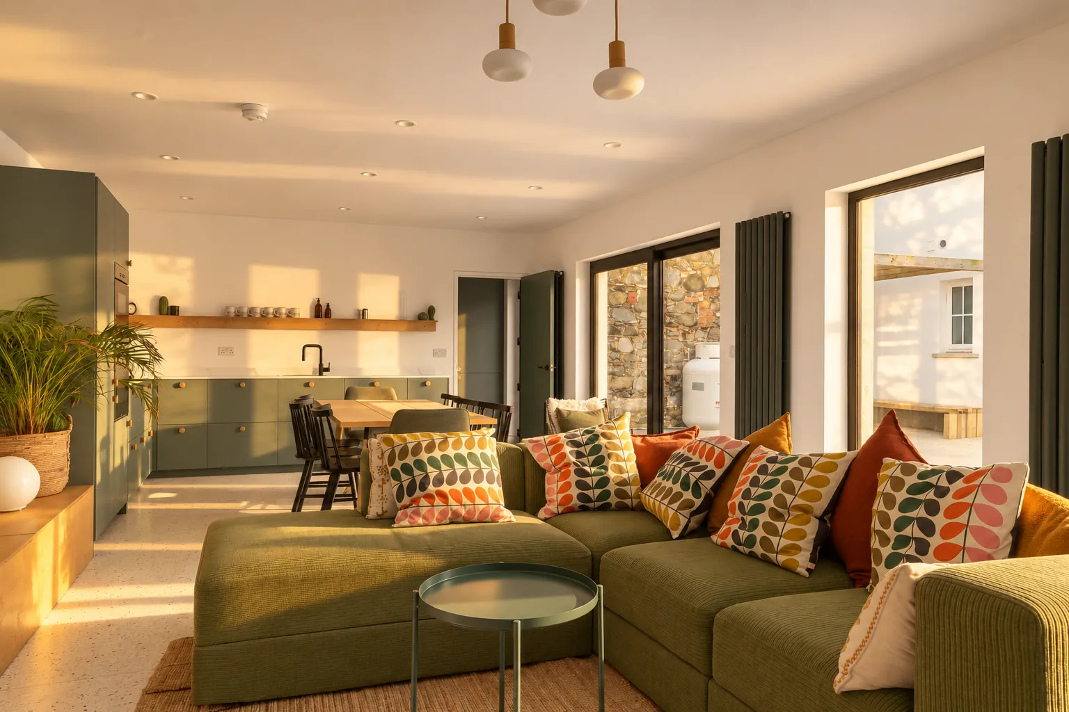 Green corner sofa and patterned cushions in a townhouse living room, low evening sun
