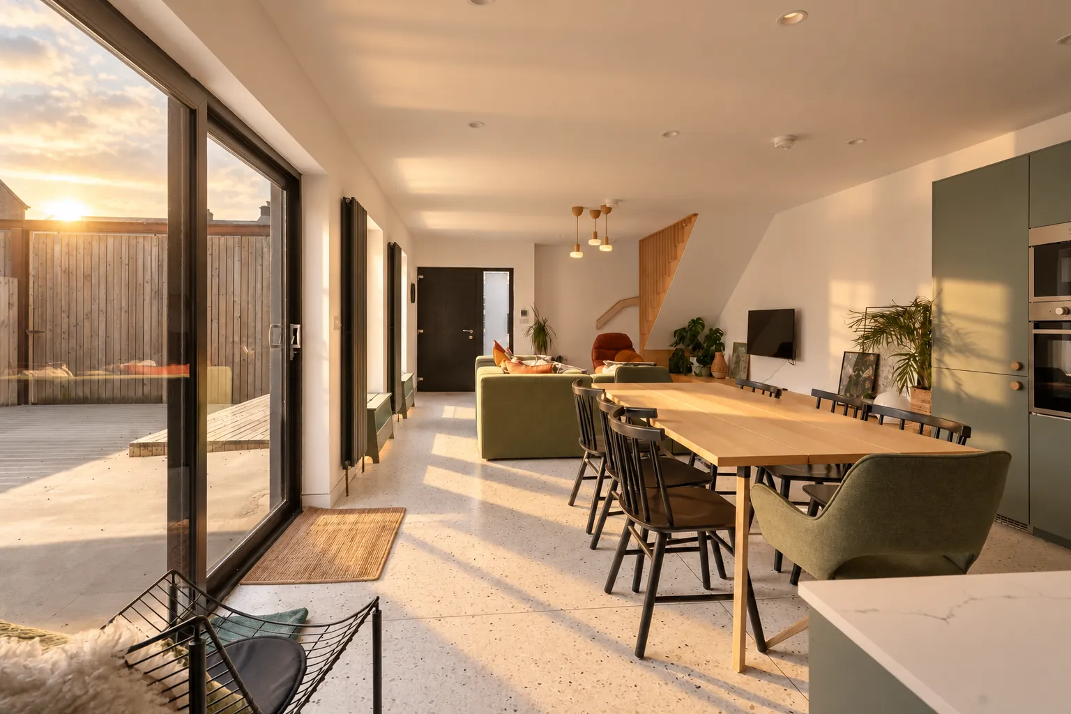 Open-plan townhouse kitchen and dining room with the sun setting through sliding doors, Northern Ireland